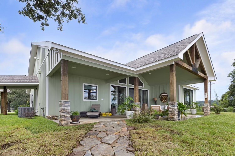 Custom-built East Texas home featuring a modern design with stone accents, large windows, and a landscaped yard, showcasing the craftsmanship of Ross Homes & Drafting.