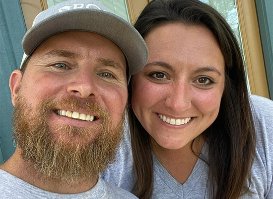Travis and Alissa Ross, custom home builders from Ross Homes & Drafting, smiling together in casual attire, embodying family values and commitment to quality craftsmanship.
